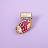This handcrafted Christmas Stocking Pin, featuring red, white, and wood-tone details, is displayed against a light purple background—perfect for adding festive charm to your holiday wardrobe.