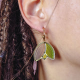 Close-up of a person’s ear with braided hair, wearing lightweight, handcrafted earrings shaped like overlapping leaf segments in brown and green tones with a gold outline.
